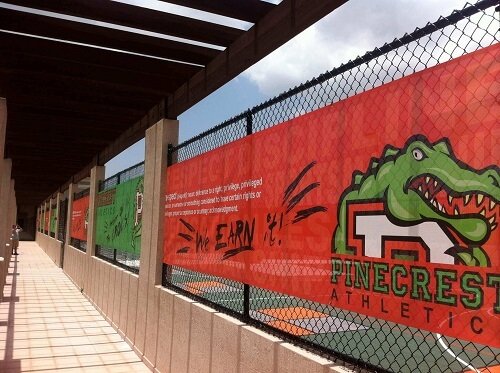 Custom mesh banner installed on chain link fence for athletic facility branding. Perforated material reduces wind resistance while maintaining high visual impact.
